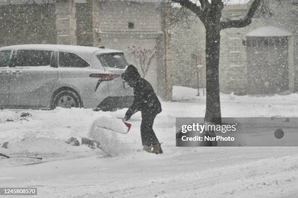 Man shoveling snow from the sidewalk in front of his home during a treacherous winter storm in Toronto, Ontario, Canada, on December 23, 2022....