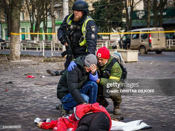 Rescuer and Ukrainian police officer confort a man as he reacts next a body of a dead woman after Russian shelling to Ukrainian city of Kherson on...