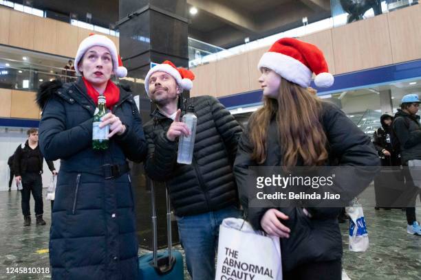 Family of three wearing Santa hats at London Euston train station on December 24, 2022 in London, England. Rail strikes over the Christmas period...