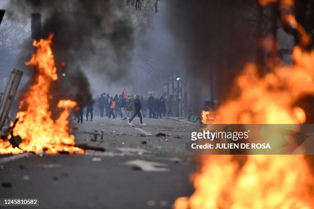 Protesters stand behind flames during clashes following a demonstration of members of the Kurdish community, a day after a gunman opened fire at a...