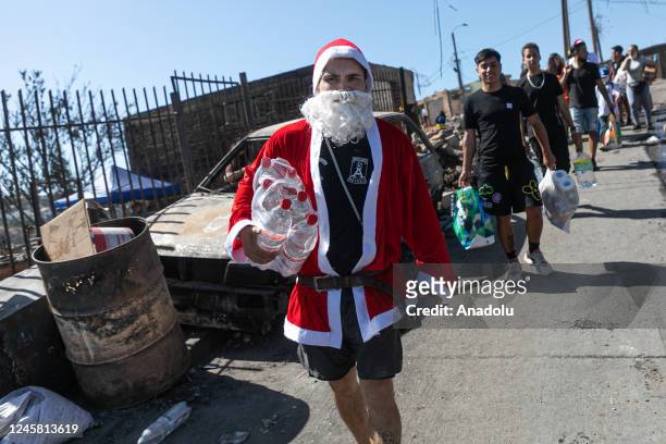 People, dressed as Santa Claus, bring gifts for children who were affected by a fire in Vina del Mar, last Thursday, on December 24, 2022 in Chile....