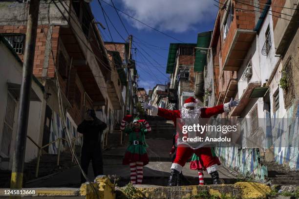 Man dressed as Santa Claus greets children from the Barrio Las Palmas de El Cementerio community, during a walk to visit children and distribute toys...