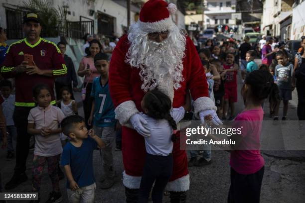 Man dressed as Santa Claus greets children from the Barrio Las Palmas de El Cementerio community, during a walk to visit children and distribute toys...