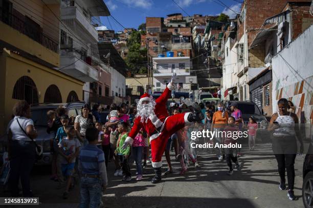 Man dressed as Santa Claus greets children from the Barrio Las Palmas de El Cementerio community, during a walk to visit children and distribute toys...