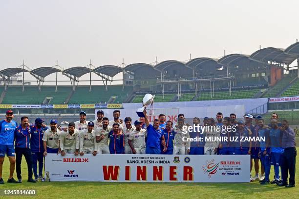 Indias cricket team poses for a photo as they hold the tournament trophy after winning on the fourth day of the second cricket Test match between...