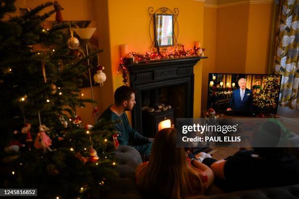 Family sits in a living room in Liverpool, as they watch Britain's King Charles III delivering his first annual Christmas Day message, on television,...