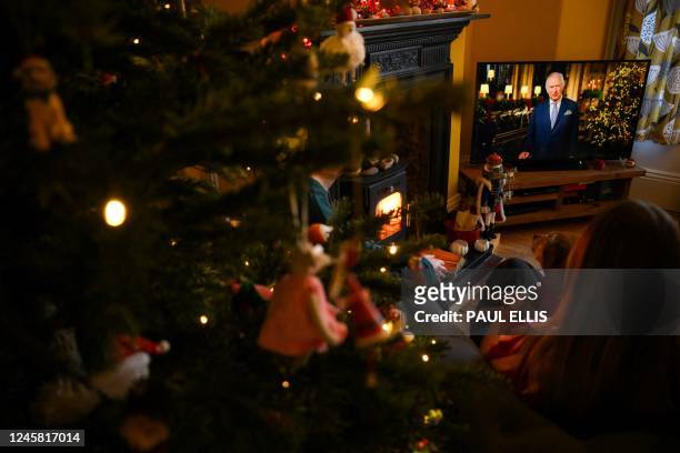 Family sits in a living room in Liverpool, as they watch Britain's King Charles III delivering his first annual Christmas Day message, on television,...