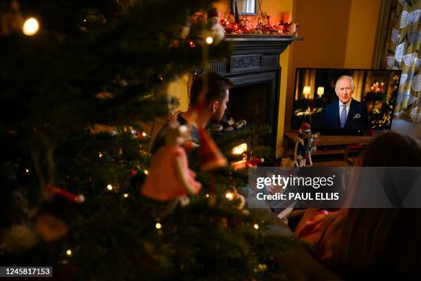 Family sits in a living room in Liverpool, as they watch Britain's King Charles III delivering his first annual Christmas Day message, on television,...