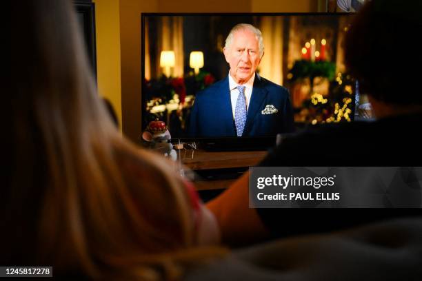 Family sits in a living room in Liverpool, as they watch Britain's King Charles III delivering his first annual Christmas Day message, on television,...