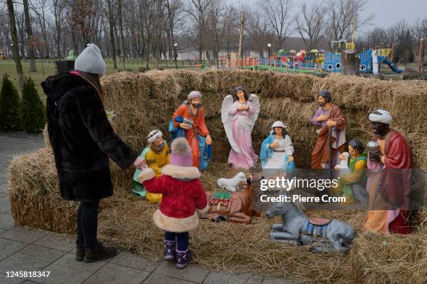 Mother and her child look at a Catholic Christian nativity scene on December 25, 2022 in Pokrovsk, Ukraine. Ukrainians celebrate Catholic Christmas...