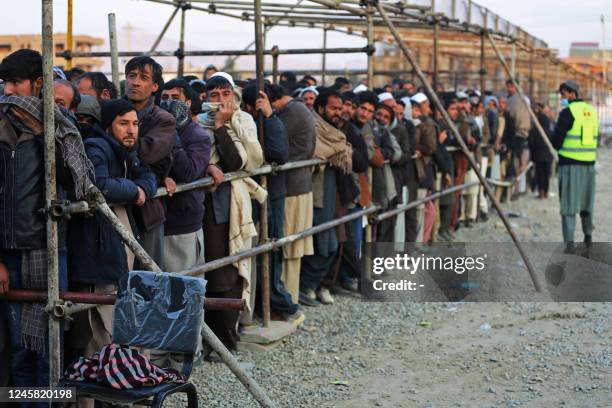 Afghan men stand in queues to receive food aid from a non-governmental organisation in Kabul on December 25, 2022. - Several foreign aid groups...