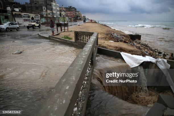 Palestinians walk through a street flooded with rainwater at Al-Shati refugee camp, west of Gaza City, on December 26, 2022.