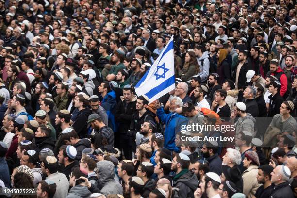 Man holds the Israeli flag as thousands of Israeli religious jews attend the funeral of their spirtual leader Rabbi Haim Druckman on December 26,...