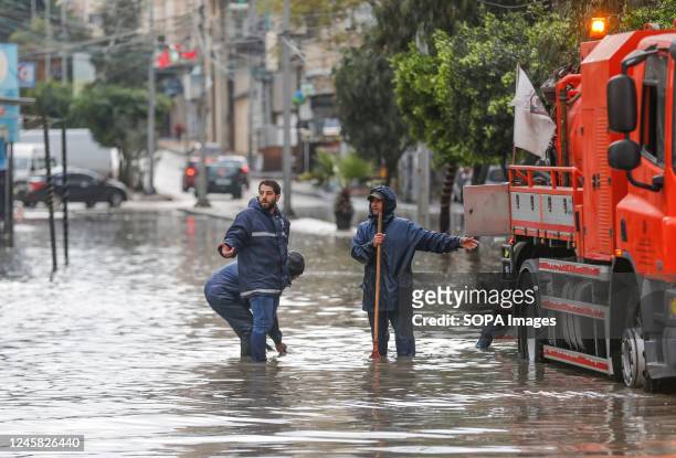 Palestinian municipality workers trying to open a road damaged by flood waters after heavy rains due to a winter storm hitting the Gaza strip in Gaza...