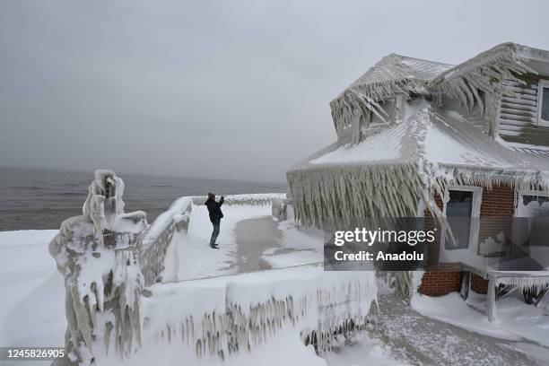 Man takes photos of a house completely covered in ice after snowfall as death toll in the snowstorm, which was effective, reached 26 in Buffalo, New...