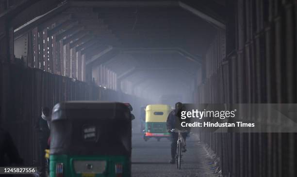 Commuters are seen wearing warm clothes on a cold and Foggy morning at Old Iron Bridge on December 26, 2022 in New Delhi, India. Dense fog blanketed...