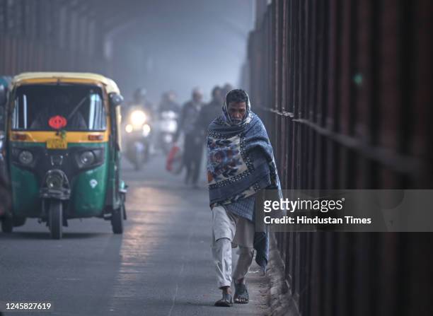 Commuters are seen wearing warm clothes on a cold and Foggy morning at Old Iron Bridge on December 26, 2022 in New Delhi, India. Dense fog blanketed...
