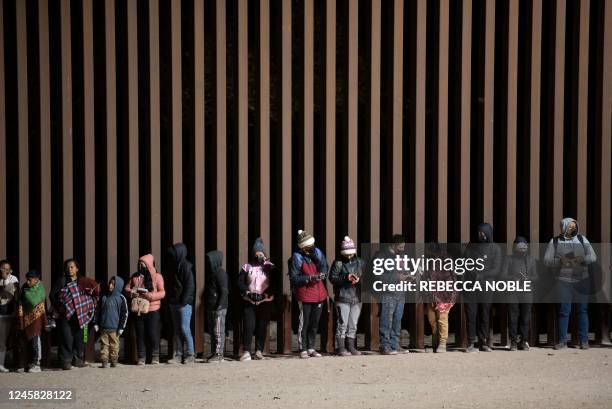 Asylum-seekers line up to be processed by US Customs and Border Patrol agents at a gap in the US-Mexico border fence near Somerton, Arizona, on...