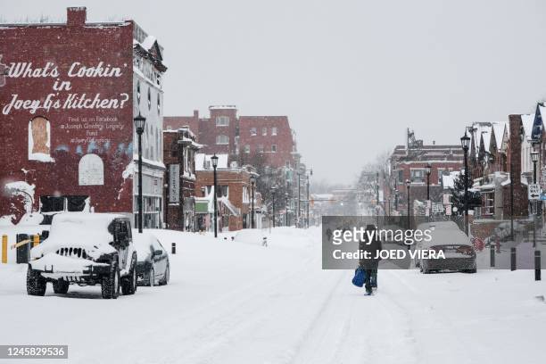 Residents walk along snow-covered streets in Buffalo, New York, on December 26, 2022. - US emergency crews counted the grim costs of a colossal...