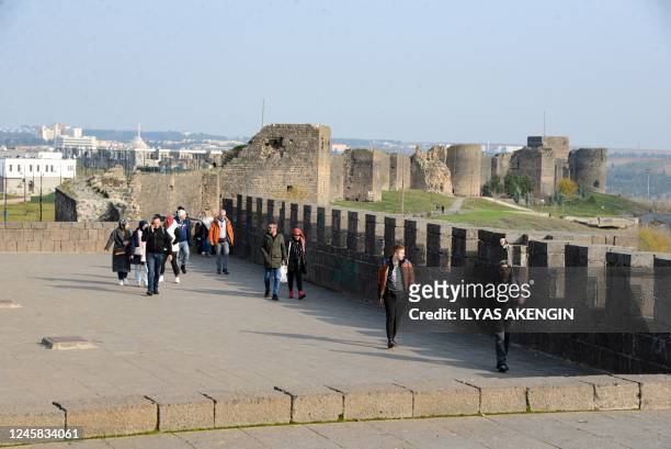 People walk on the historical city walls in the historical Sur district in Diyarbakir on December 23, 2022. - Bullet marks reveal the spot where a...