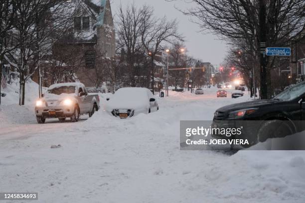 Vehicles make their way along a snow-covered street in Buffalo, New York, on December 26, 2022. - Emergency crews in New York were scrambling on...
