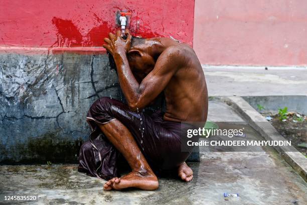 Rohingya refugee bathes at a temporary shelter after arriving by boat in Laweueng, Aceh province on December 27, 2022. - Rohingya refugees received...