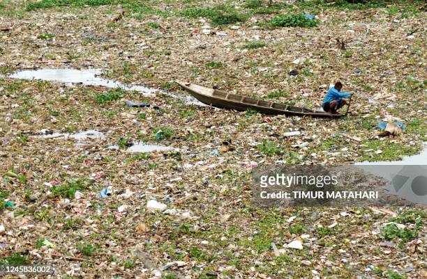Man collects recyclable plastic in the polluted Citarum river in Bandung, West Java on December 27, 2022.