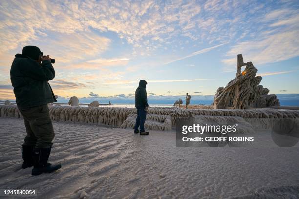 Person photographs a pier covered in ice in Port Stanley, Ontario, Canada, on December 27, 2022. The ice formations were created by a large winter...