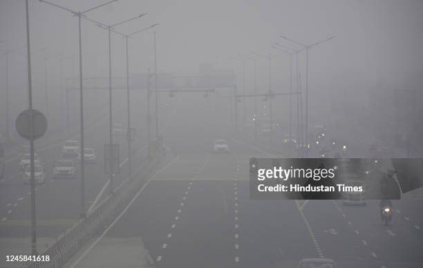 Commuters drive at slow speed with light amid cold and dense foggy morning at the Delhi-Meerut Expressway Dasna on December 27, 2022 in Ghaziabad,...