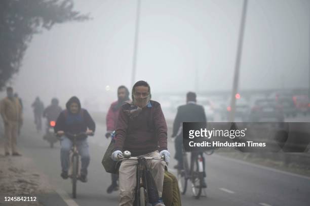 Company workers going to work on a bicycle amid cold and foggy morning at National Highway-48 service road near Udyog Vihar on December 27, 2022 in...