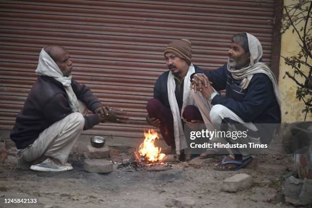 People sitting around a bonfire to protect themselves from winter on a cold foggy morning at Kadipur road near Shiv Nagar on December 27, 2022 in...