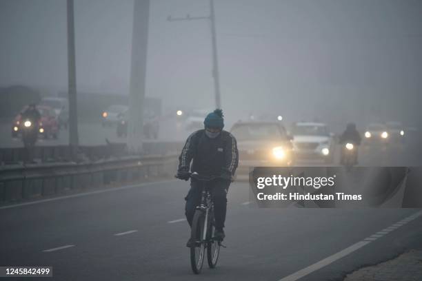 Commuters are seen wearing warm clothes amid cold and foggy morning at National Highway-48 service road near Udyog Vihar on December 27, 2022 in...