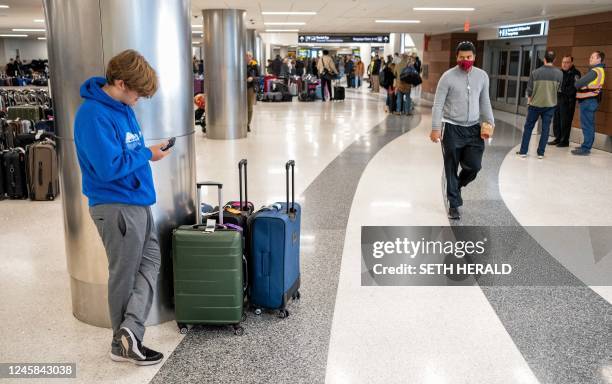 Traveller looks at their cellphone near the Southwest Airlines baggage claim area at the Nashville International Airport after the airline cancelled...