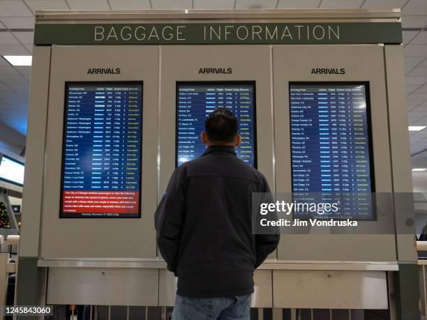 Man looks at the arrival board in the baggage claim area at Midway Airport on December 27, 2022 in Chicago, Illinois. A snowstorm and severe cold...