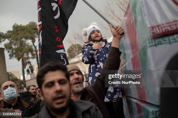 An Iranian young girl beats herself as she stands alongside coffins containing remaining of bodies of Iranian warriors who have been killed during...