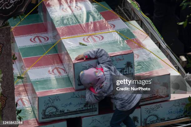 An Iranian young girl mourns while standing alongside of coffins containing remaining of bodies of Iranian warriors who have been killed during the...