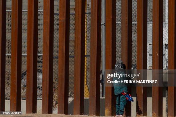 Venezuelan migrant George stands by the bars of the border wall holding a Captain America action figure while staying with his family on the Rio...