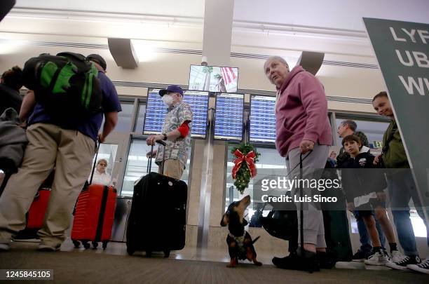 Stephanie Commerford and her dog Pickle wait in line at the Southwest Airlines terminal at John Wayne Airport in Orange County on Tuesday, Dec. 27,...