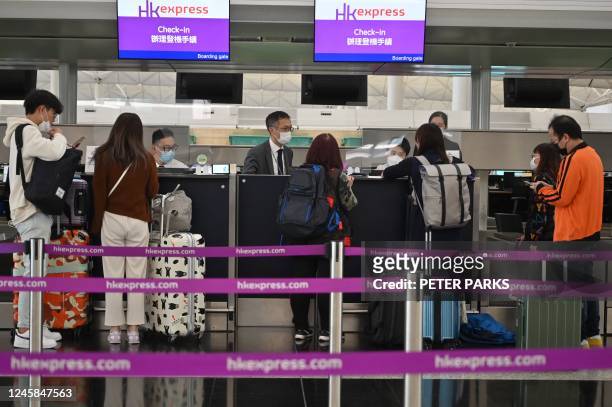 Passengers check-in at the HK Express counter at the international airport in Hong Kong on December 28, 2022. - Hong Kong authorities on December 28...