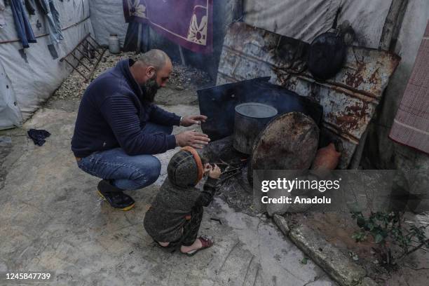 Father and son light the stove at Ataa Refugee Camp, where civilians are displaced by the attacks of Bashar Assad regime as they struggle with harsh...