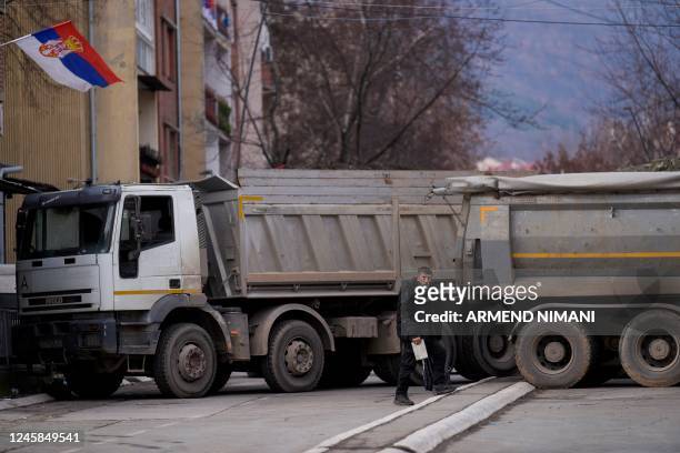 Pedestrian walks past a new road barricade set up in the divided town of Mitrovica on December 28, 2022. - On December 10, 2022 Serbs in northern...
