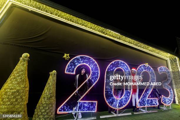 Palestinian girls pose for pictures near a lit 2023 sign ahead of New Year's celebrations in Gaza City, on December 28, 2022.