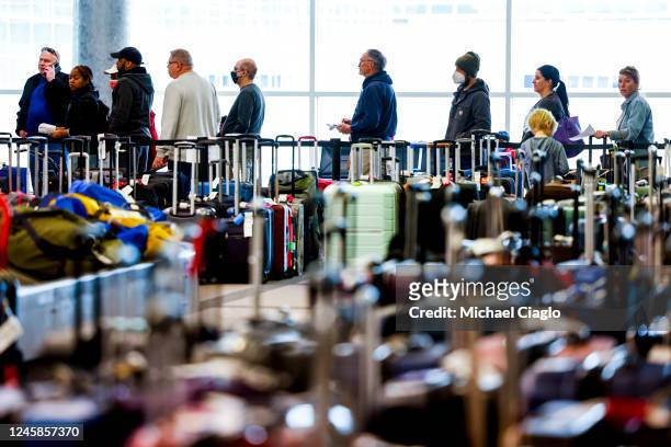 Travelers wait in line before they are allowed to search for their luggage in a baggage holding area for Southwest Airlines at Denver International...