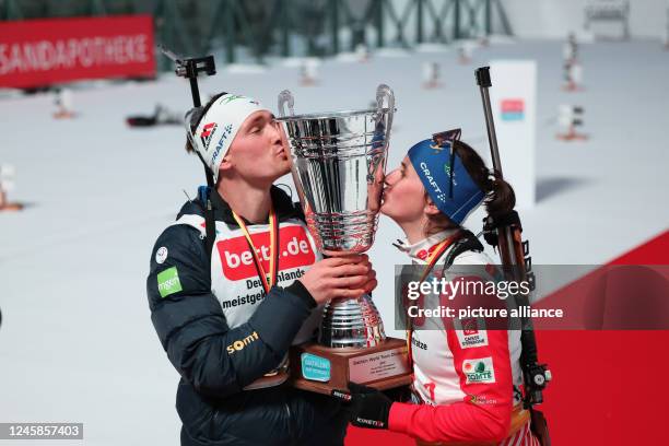 Dpatop - 28 December 2022, North Rhine-Westphalia, Gelsenkirchen: French biathletes Fabien Claude and Julia Simon kiss the winner's trophy after...