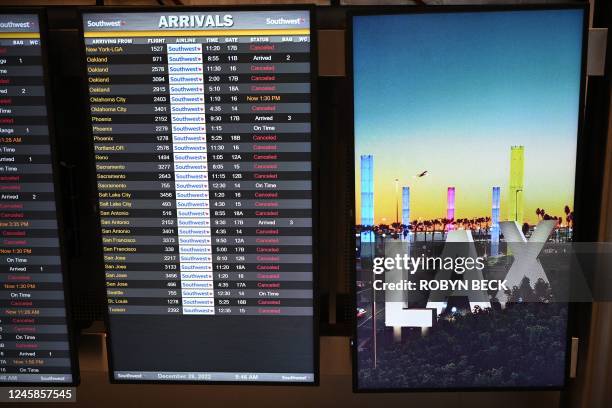 Digital display shows cancelled flights in the Southwest Airlines luggage area, December 28, 2022 at Los Angeles International Airport in Los...