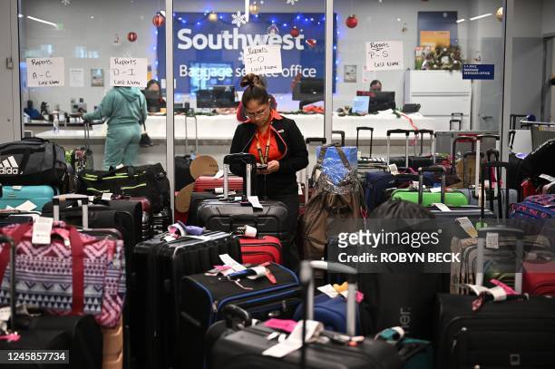 Southwest Airlines ground crew member organizes unclaimed luggage at the Southwest Airlines luggage area, December 28, 2022 at Los Angeles...
