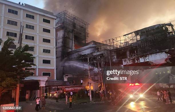 Firefighters spray water onto the site of a fire at the Grand Diamond City hotel-casino in Poipet on December 29, 2022. - As many as 10 people have...