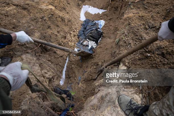 Ukranian criminal investigators and police investigate the scene after exhuming the bodies of victims in the Kyiv suburb of Irpin on April 18, 2022...