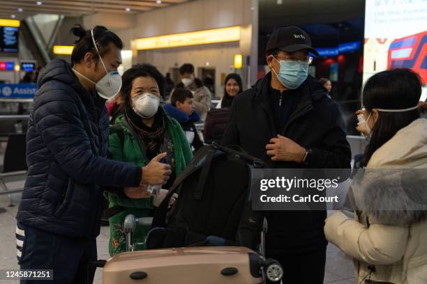 Woman sprays sanitiser on a man as they arrive at Heathrow airport on a flight from Shanghai on December 29, 2022 in London, United Kingdom....