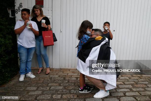 Fan of Brazilian football legend Pele wrapped in a flag of Brazilian team Santos, embraces a girl in front of the Albert Einstein Israelite Hospital,...